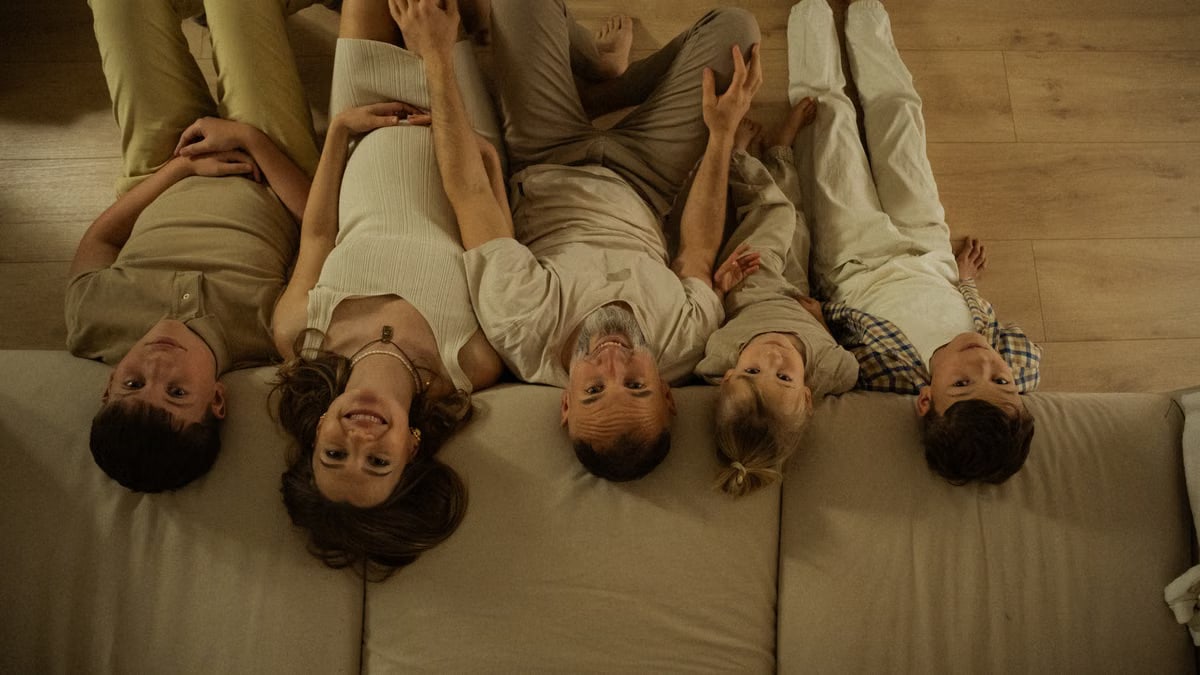 Five family members relaxing together at home, enjoying a warm moment on the floor with smiles.
